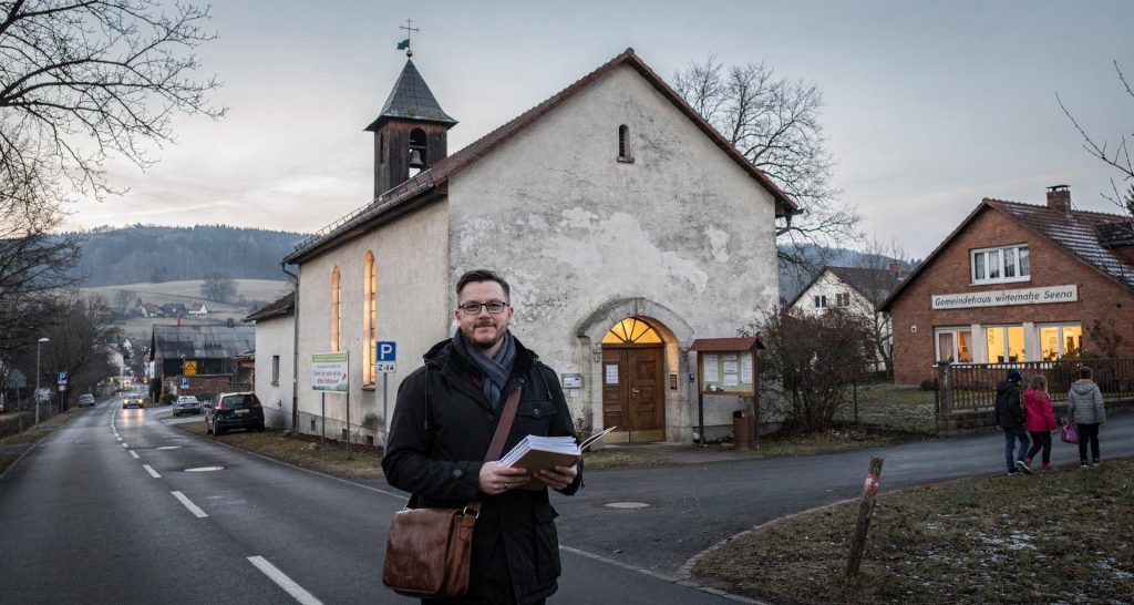 Kantor und Oberlehrer Jannik Reus vor der Kirche von Seena